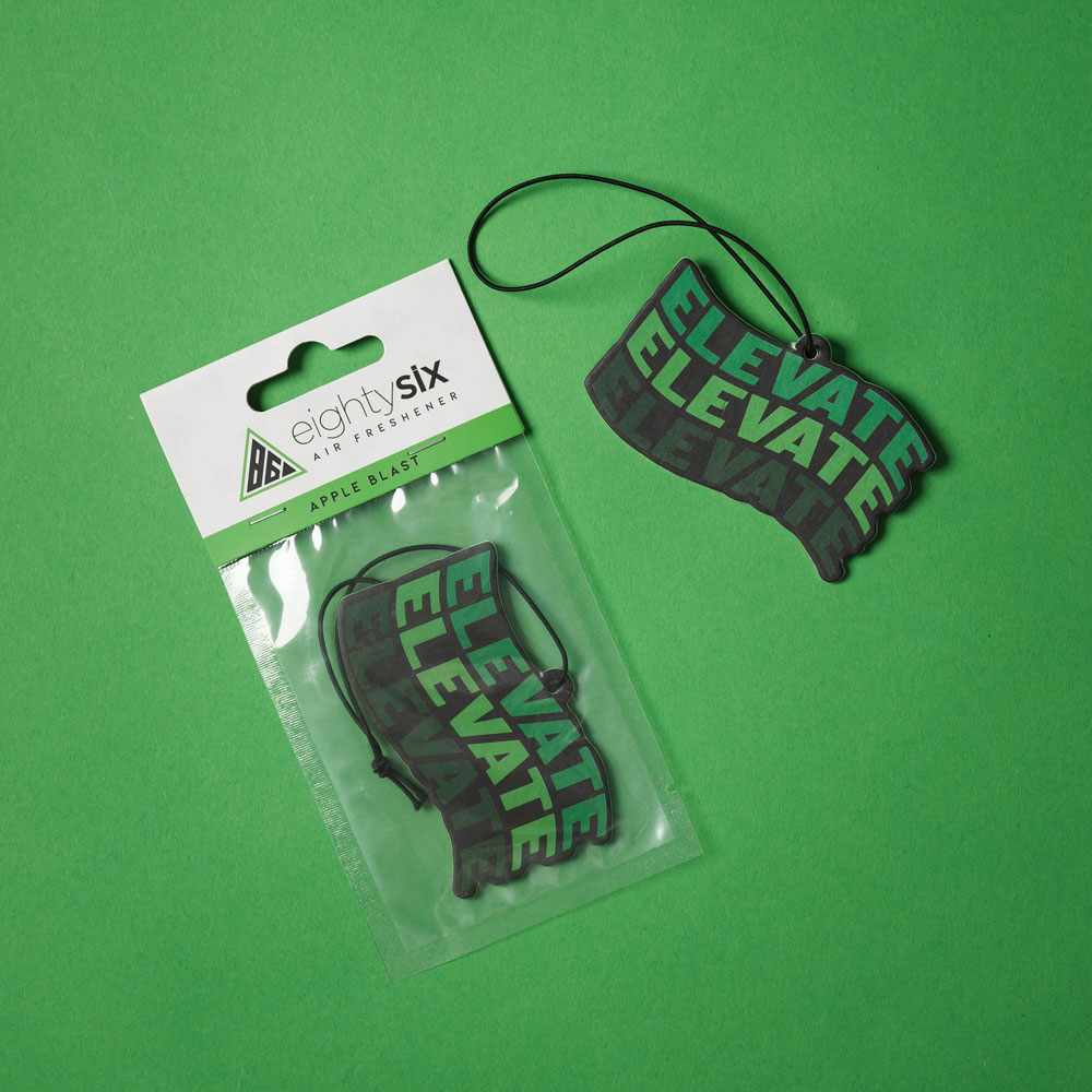 Apple Blast Eighty Six Air Freshener Apple Blast Air Freshener and its respective packaging on a green background.