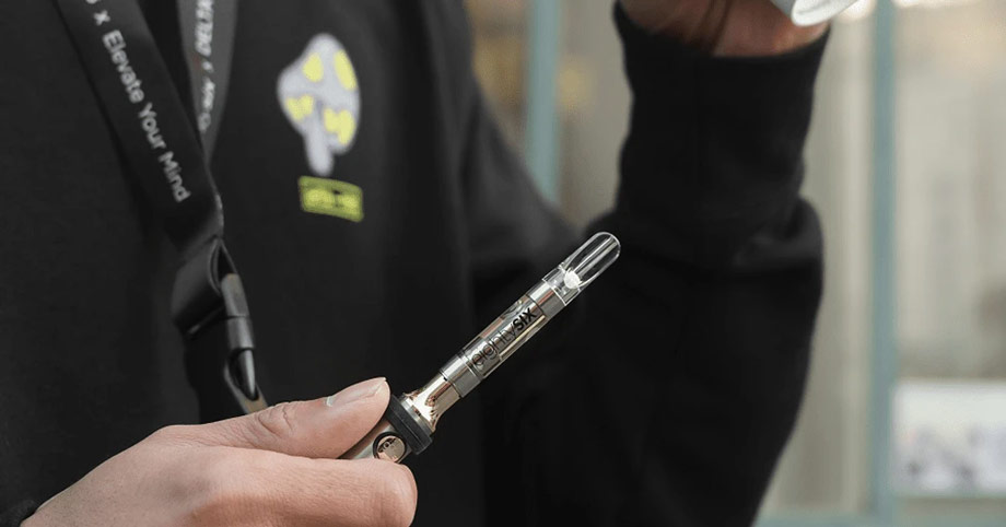 Person holding a Delta-8 vape cartridge attached to a vape battery